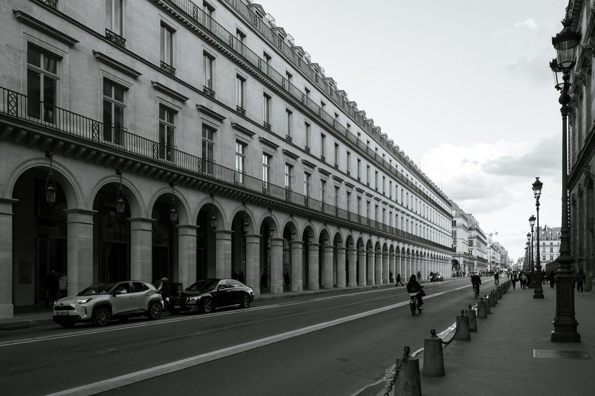 Une grande rue parisienne bordée d'arcades, avec des voitures en stationnement