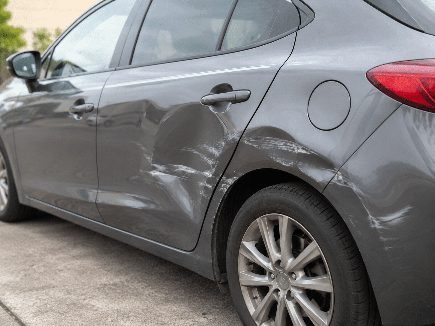 Portière de voiture rayée et enfoncée après un choc de parking à Paris, avant réparation chez NAWCAR