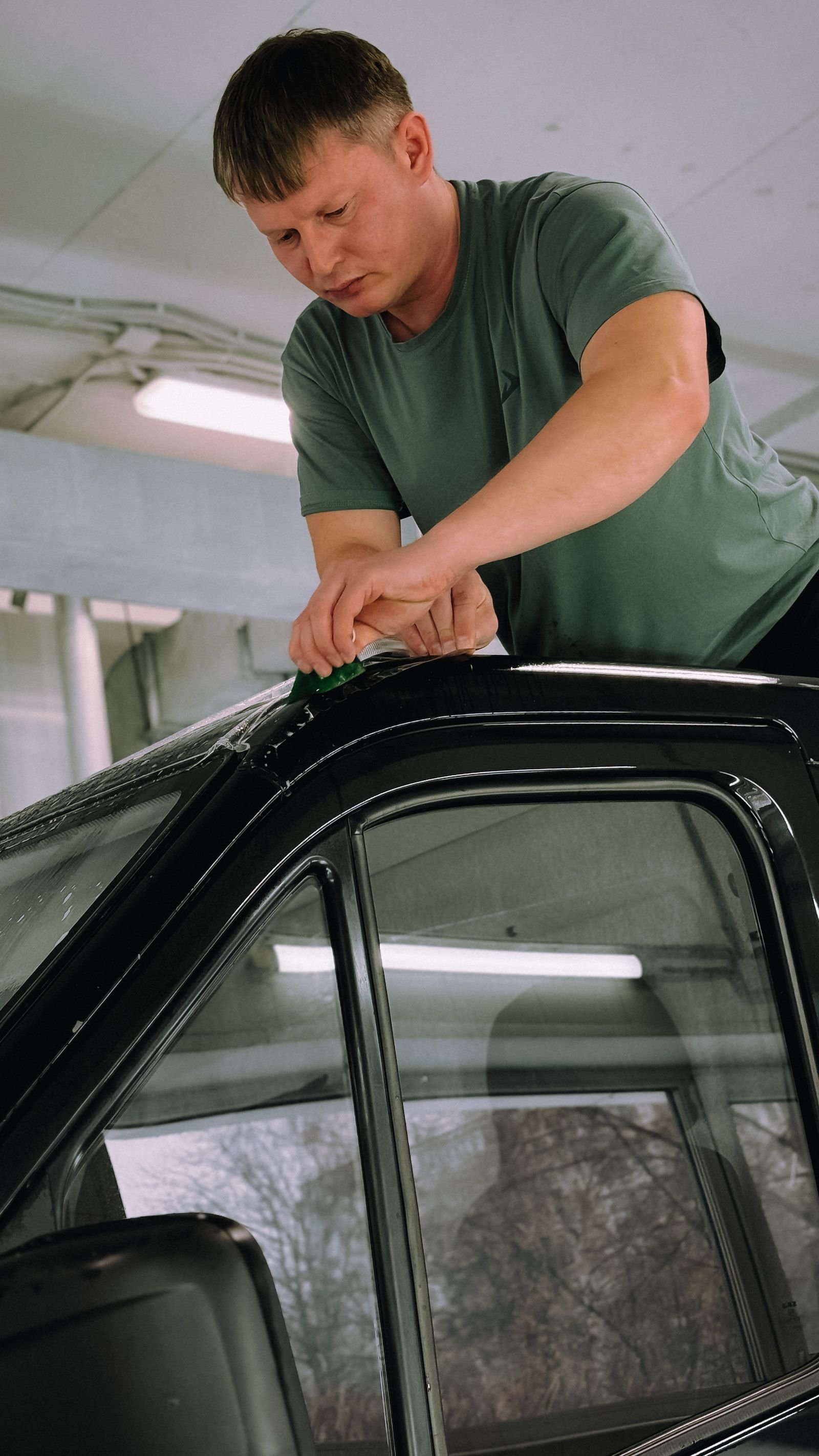 Pose d'un film teinté au maroufleur sur les vitres d'une voiture en atelier