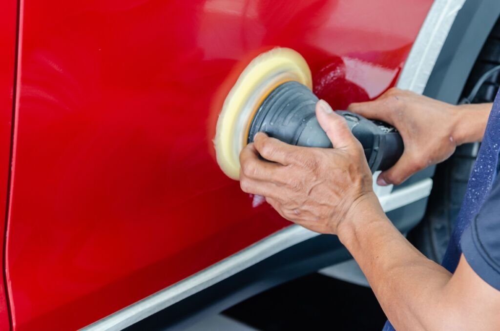 Polisseuse orbitale passée sur l'aile rouge d'une voiture pour la finition de la carrosserie