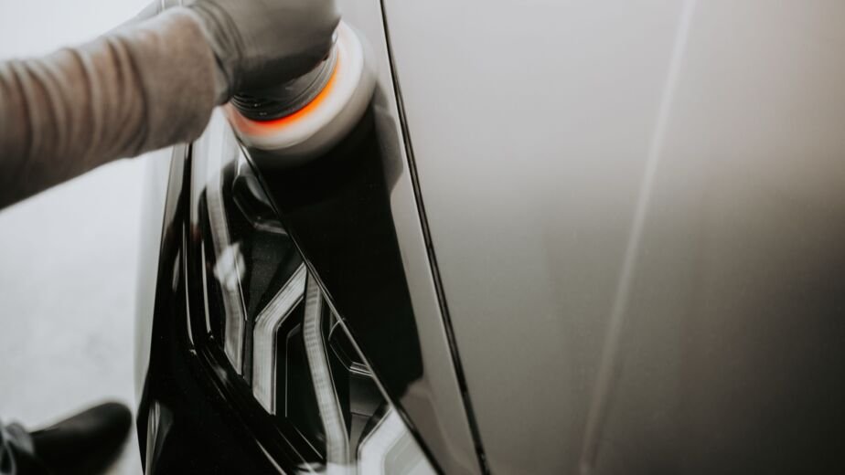 Polissage de la carrosserie d'une voiture noire avec une polisseuse avant la revente