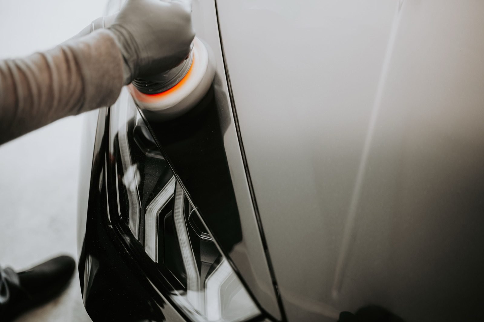 Polissage de la carrosserie d'une voiture noire avec une polisseuse avant la revente